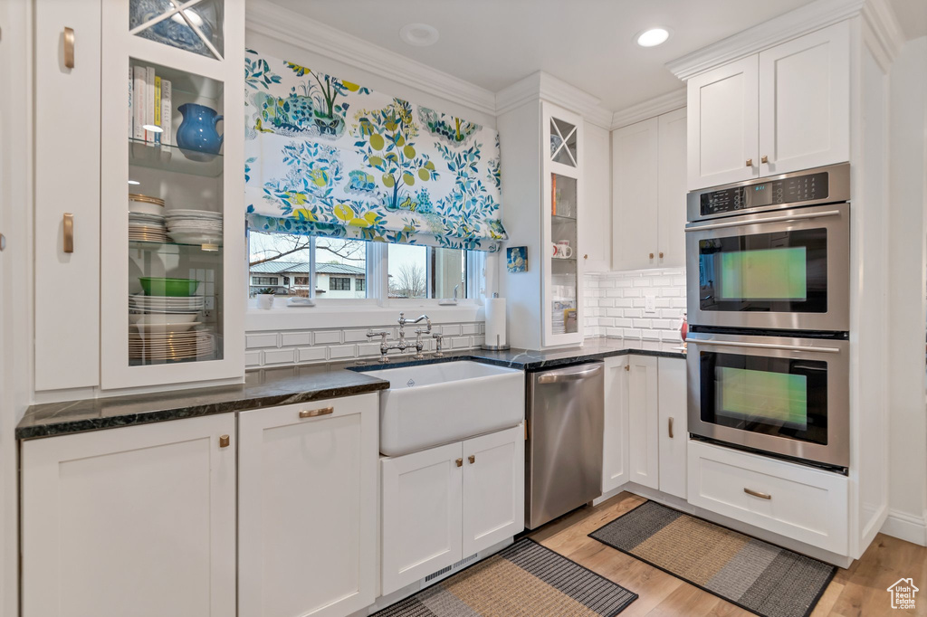 Kitchen featuring white cabinetry, backsplash, sink, and stainless steel appliances