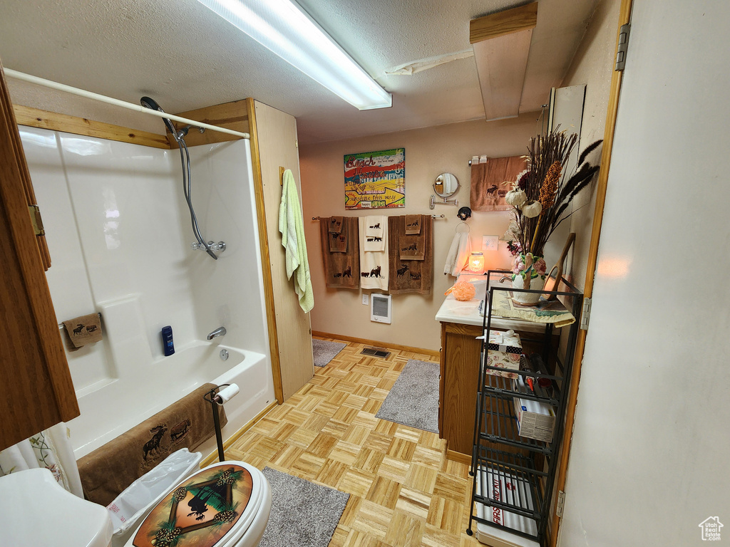 Full bathroom with vanity, bathtub / shower combination, parquet flooring, a textured ceiling, and toilet