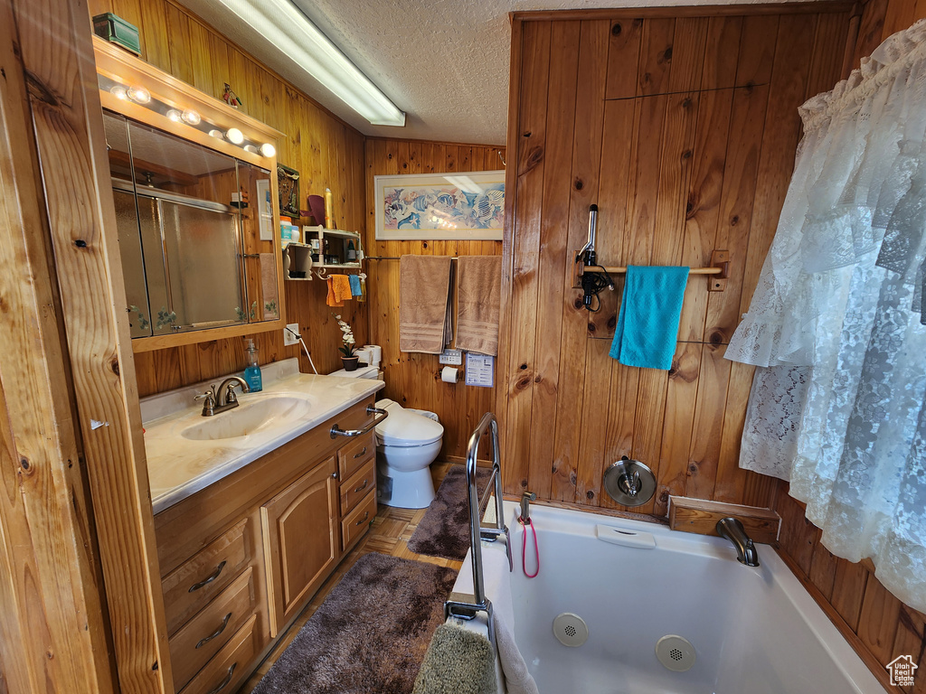 Bathroom with vanity, wooden walls, a textured ceiling, and toilet