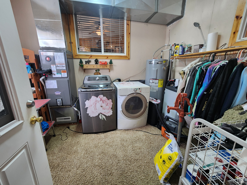 Washroom featuring heating utilities, electric water heater, washing machine and dryer, and carpet flooring