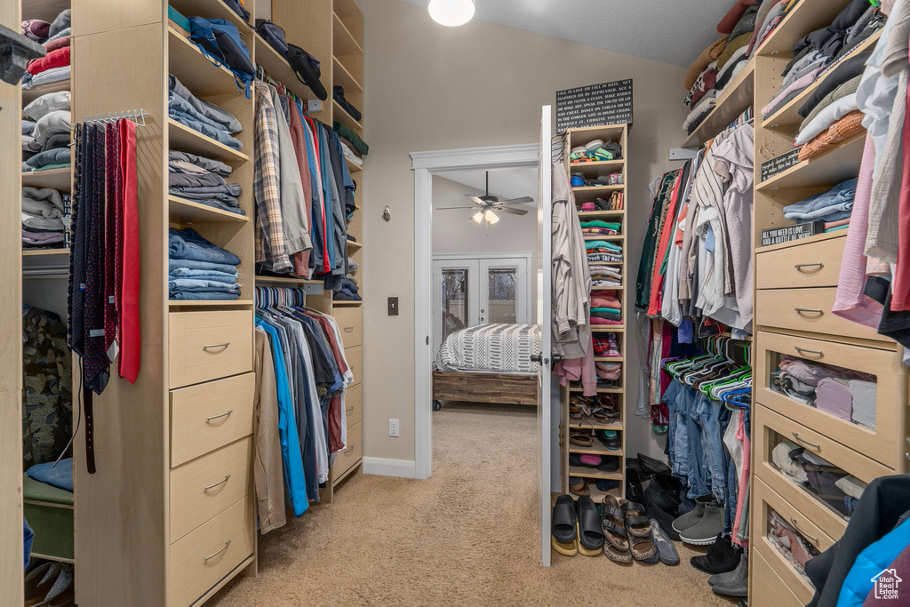 Walk in closet with light colored carpet and ceiling fan