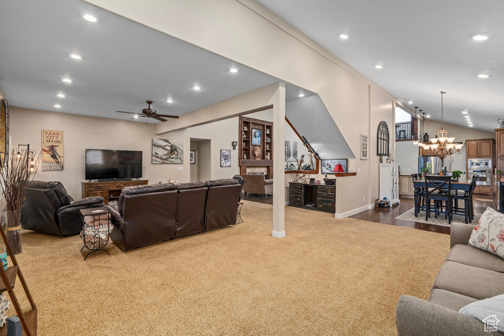 Living room featuring carpet floors, ceiling fan with notable chandelier, and lofted ceiling