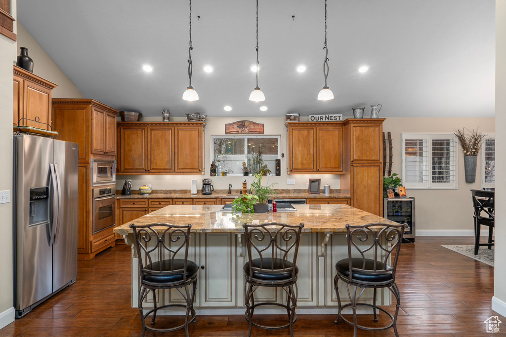 Kitchen featuring hanging light fixtures, a kitchen island, appliances with stainless steel finishes, and dark hardwood / wood-style flooring