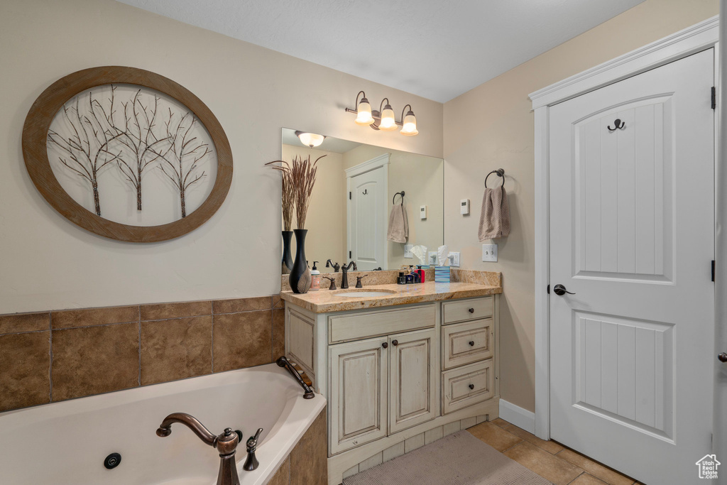 Bathroom featuring vanity, tile flooring, and a tub