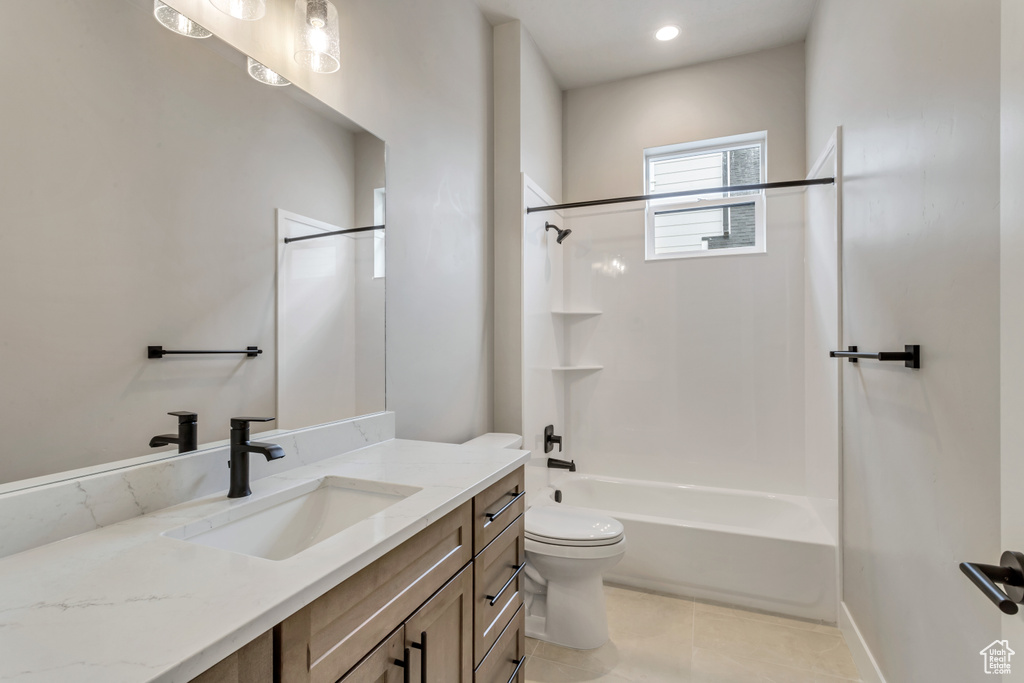 Full bathroom featuring  shower combination, tile floors, vanity with extensive cabinet space, and toilet