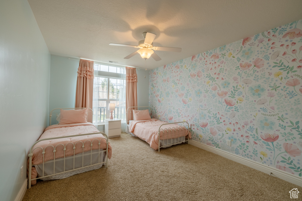 Bedroom with light carpet, a textured ceiling, and ceiling fan