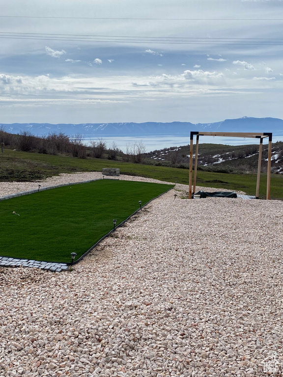 Surrounding community with a mountain view and a lawn