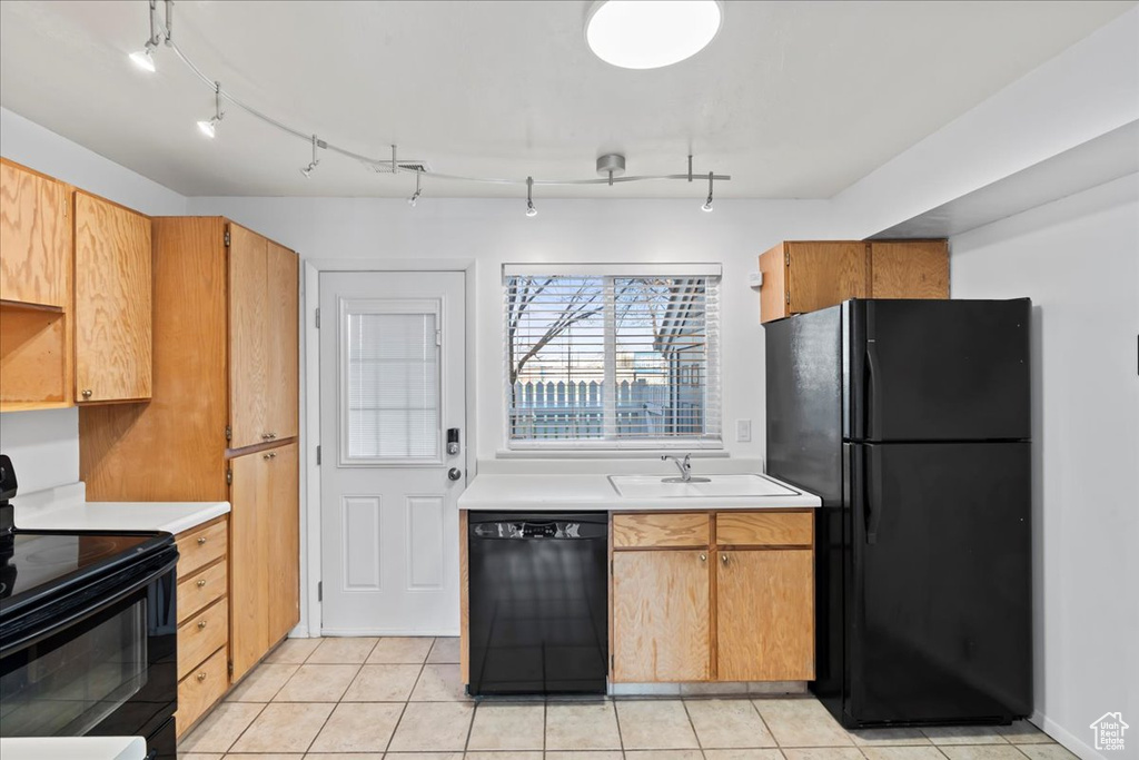 Kitchen featuring rail lighting, sink, light tile floors, and black appliances