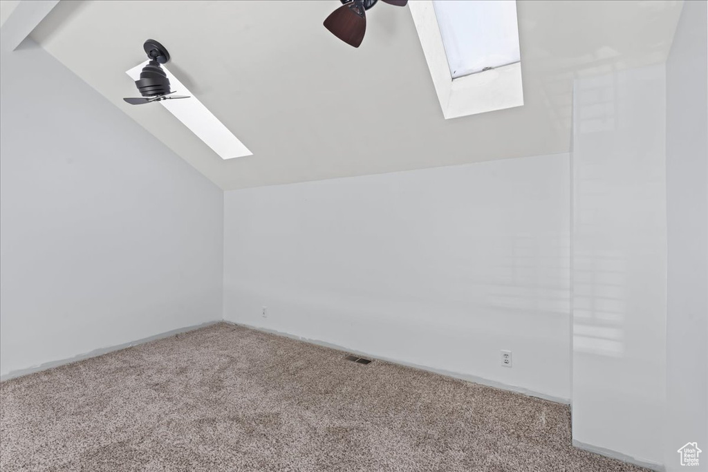 Bonus room with carpet, vaulted ceiling with skylight, and ceiling fan