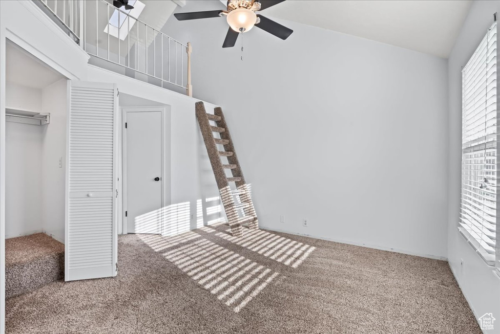 Unfurnished bedroom featuring a high ceiling, a closet, ceiling fan, and carpet