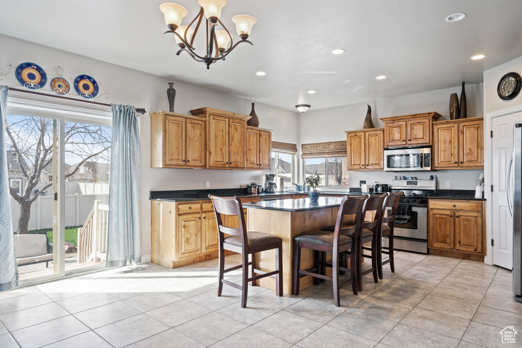 Kitchen with a kitchen breakfast bar, a center island, a notable chandelier, light tile flooring, and range