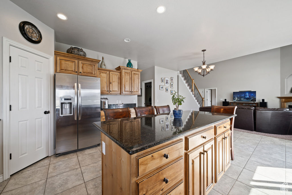 Kitchen featuring stainless steel fridge with ice dispenser, a kitchen island, hanging light fixtures, a chandelier, and light tile flooring