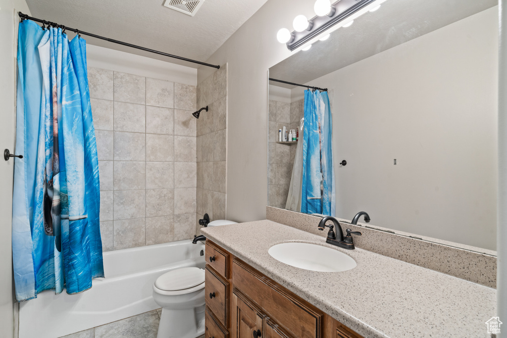 Full bathroom featuring shower / bath combo, oversized vanity, toilet, and tile flooring