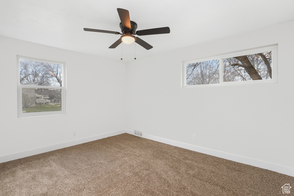 Empty room with a healthy amount of sunlight, carpet flooring, and ceiling fan