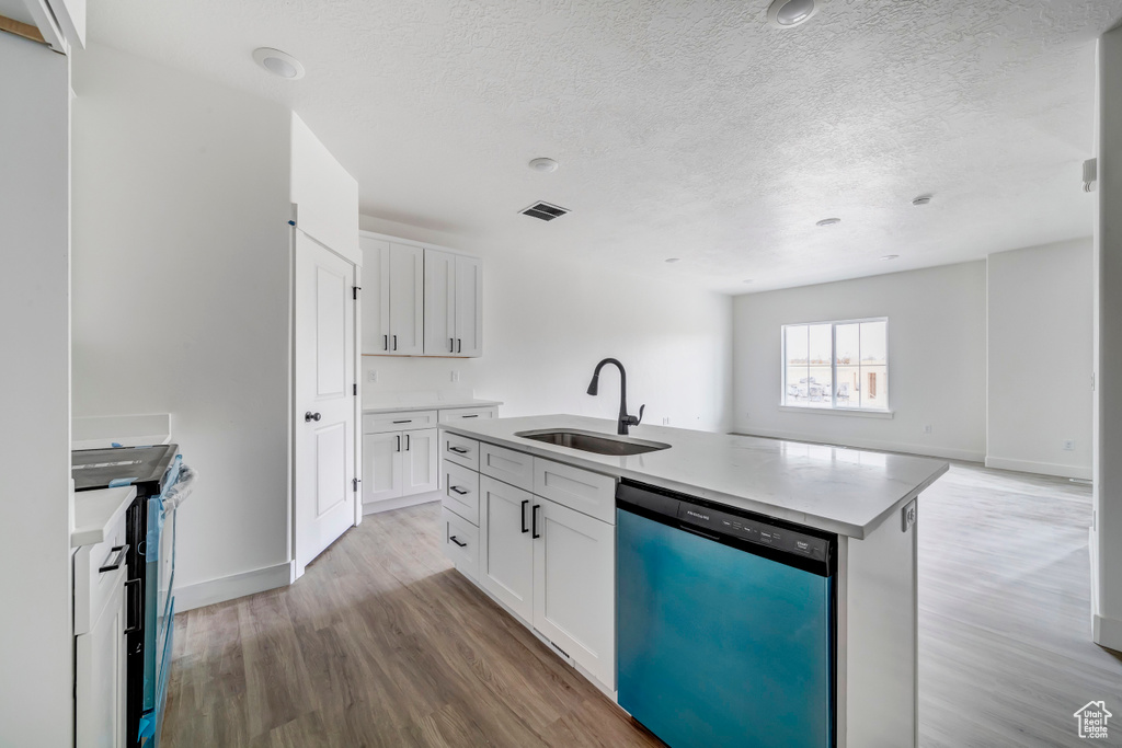 Kitchen with a center island with sink, light wood-type flooring, white cabinets, and stainless steel dishwasher