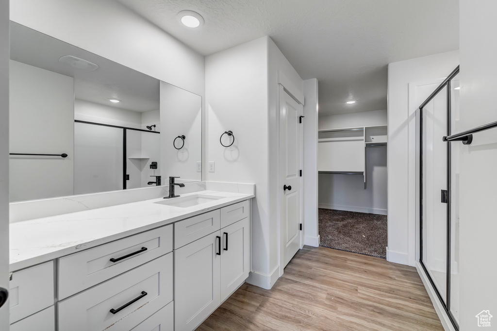 Bathroom with walk in shower, hardwood / wood-style floors, and vanity