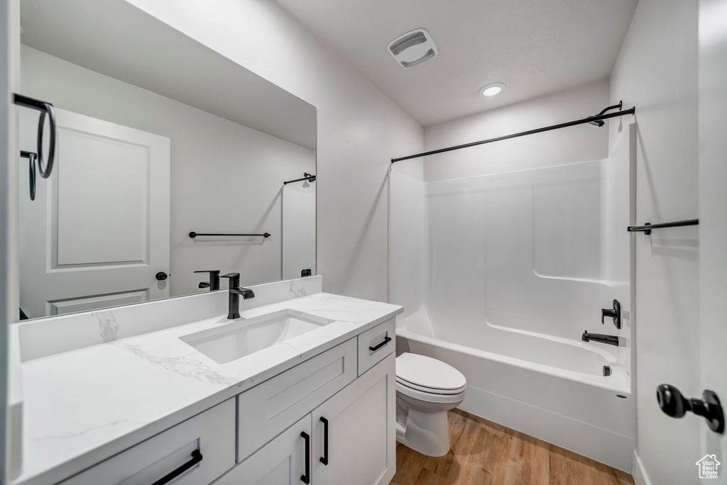 Full bathroom featuring shower / washtub combination, toilet, vanity, and hardwood / wood-style flooring