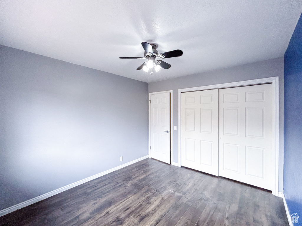 Unfurnished bedroom with a closet, ceiling fan, and dark hardwood / wood-style flooring