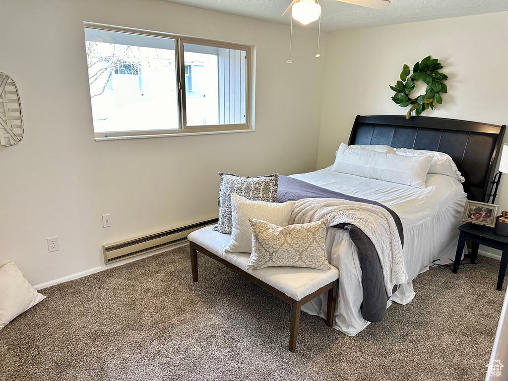 Carpeted bedroom featuring ceiling fan and a baseboard heating unit