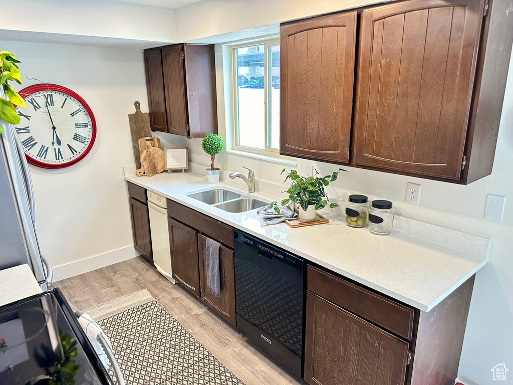 Kitchen featuring white dishwasher, light hardwood / wood-style floors, dark brown cabinetry, dishwasher, and sink