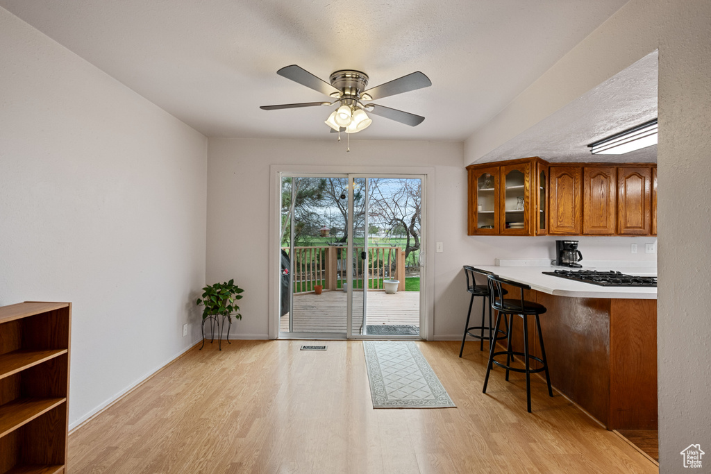 Kitchen featuring ceiling fan, kitchen peninsula, light hardwood / wood-style flooring, and a breakfast bar