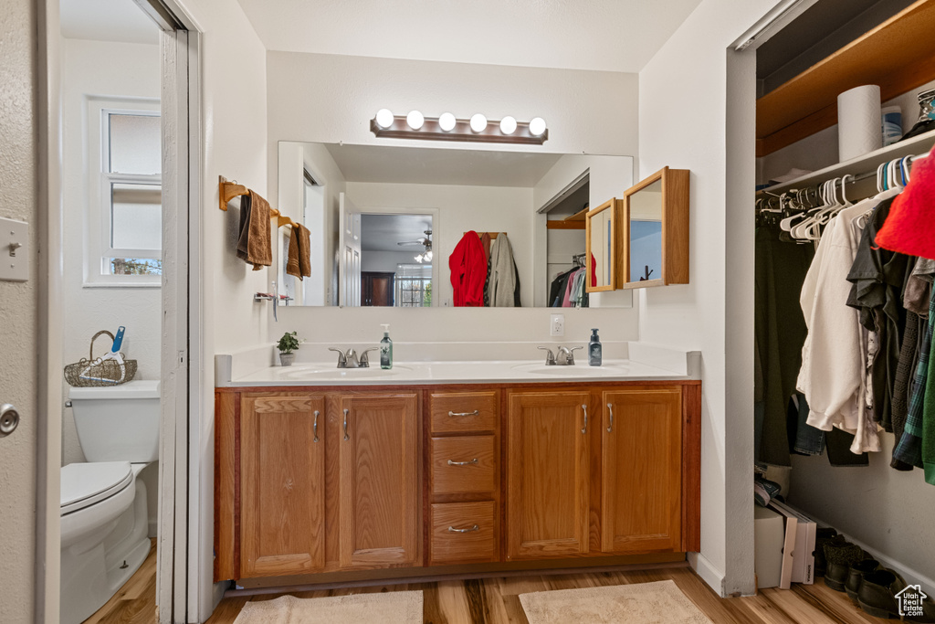 Bathroom featuring toilet, hardwood / wood-style floors, double sink, and vanity with extensive cabinet space
