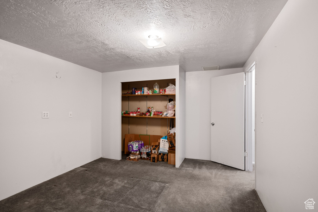 Basement featuring a textured ceiling and dark carpet