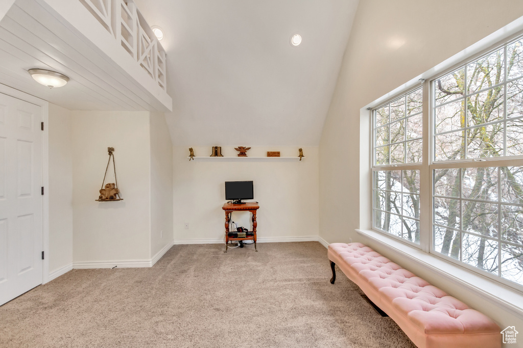 Living area with plenty of natural light, high vaulted ceiling, and light colored carpet