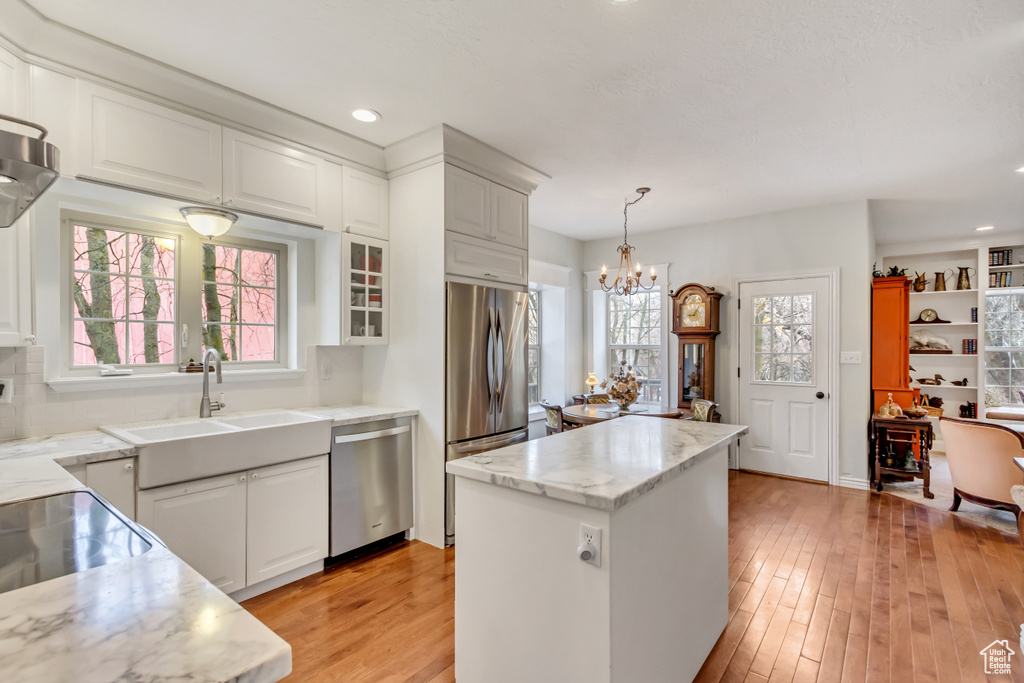 Kitchen with a notable chandelier, stainless steel appliances, decorative light fixtures, and a wealth of natural light
