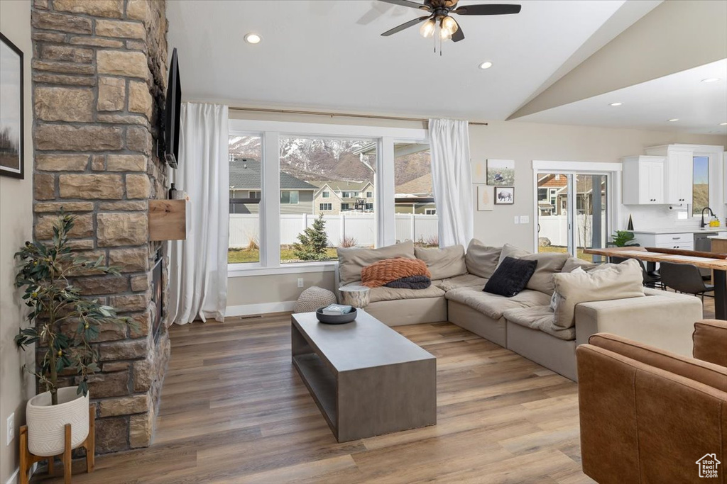 Living room featuring plenty of natural light, ceiling fan, vaulted ceiling, and light hardwood / wood-style flooring