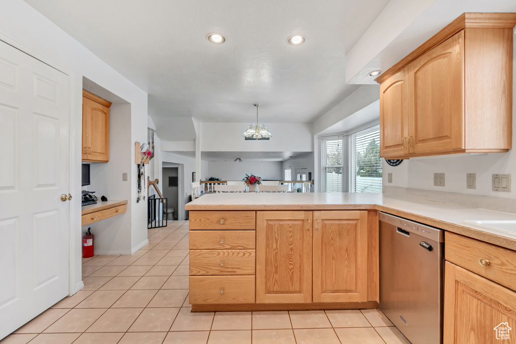 Kitchen featuring hanging light fixtures, kitchen peninsula, light tile floors, and stainless steel dishwasher