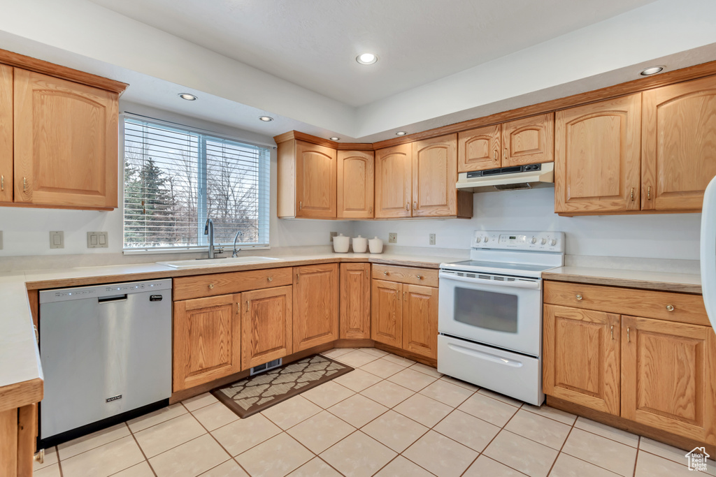 Kitchen with white range with electric cooktop, dishwasher, sink, and light tile flooring