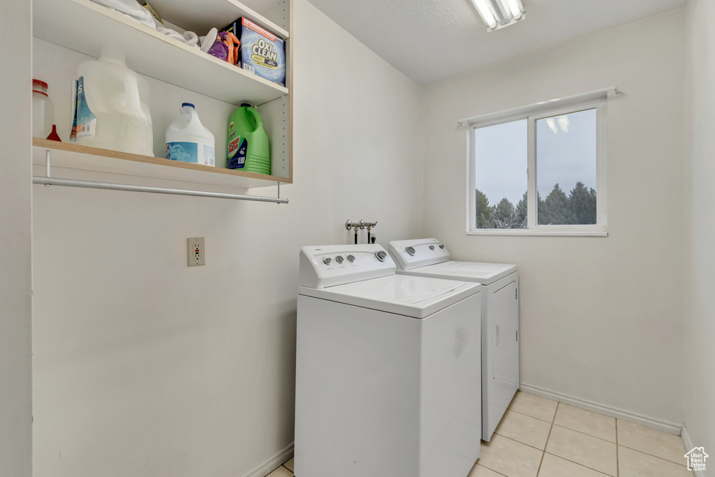 Laundry room featuring light tile floors, hookup for a washing machine, and washing machine and dryer