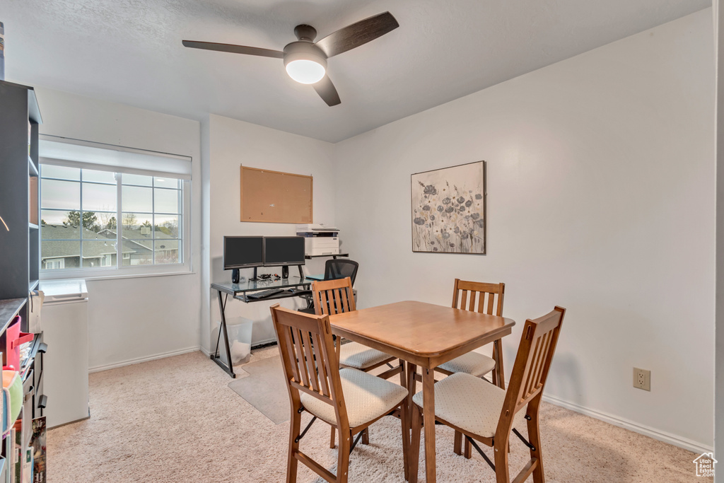 Carpeted dining area featuring ceiling fan