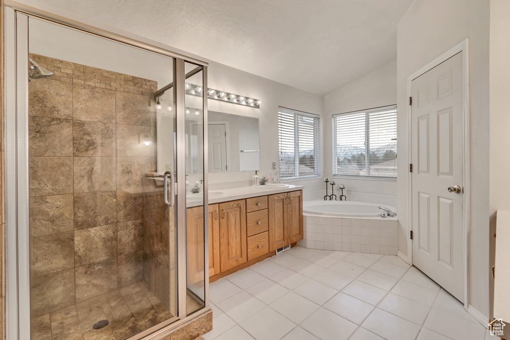 Bathroom featuring tile floors, plus walk in shower, vaulted ceiling, and dual vanity