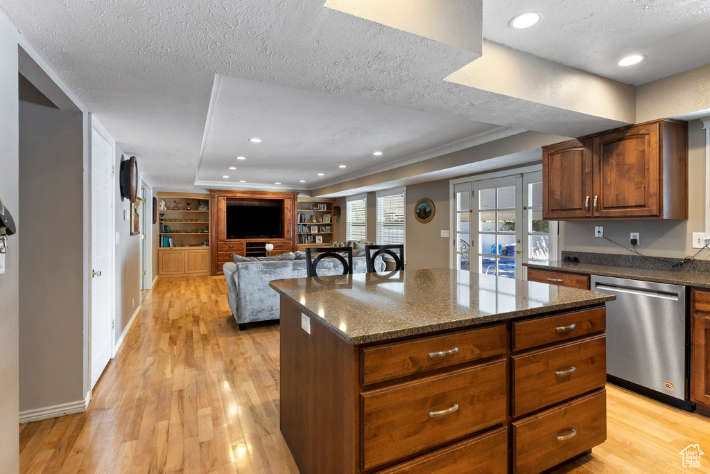 Kitchen featuring light hardwood / wood-style flooring, a kitchen island, a textured ceiling, and stainless steel dishwasher