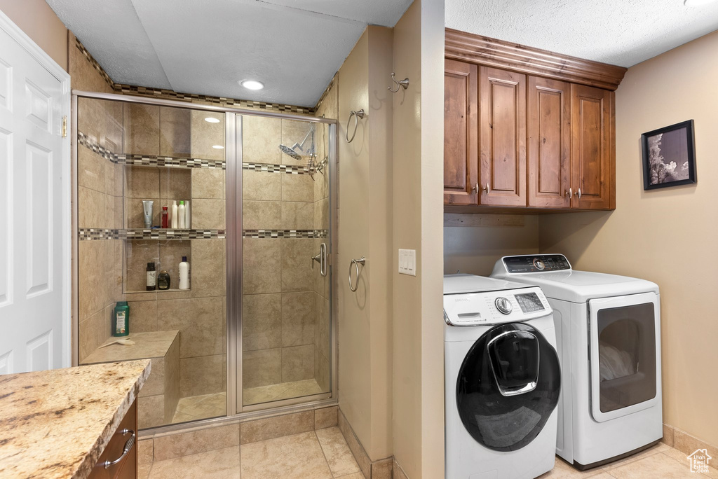 Laundry room featuring light tile floors, cabinets, and washing machine and dryer