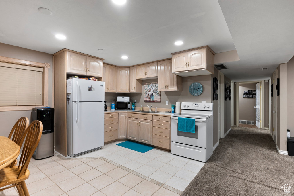 Kitchen featuring white appliances, light carpet, sink, and light brown cabinetry