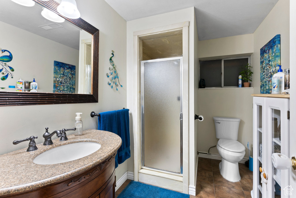 Bathroom featuring vanity, tile floors, a shower with shower door, and toilet