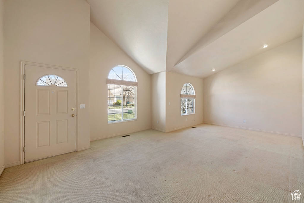 Carpeted entryway featuring high vaulted ceiling