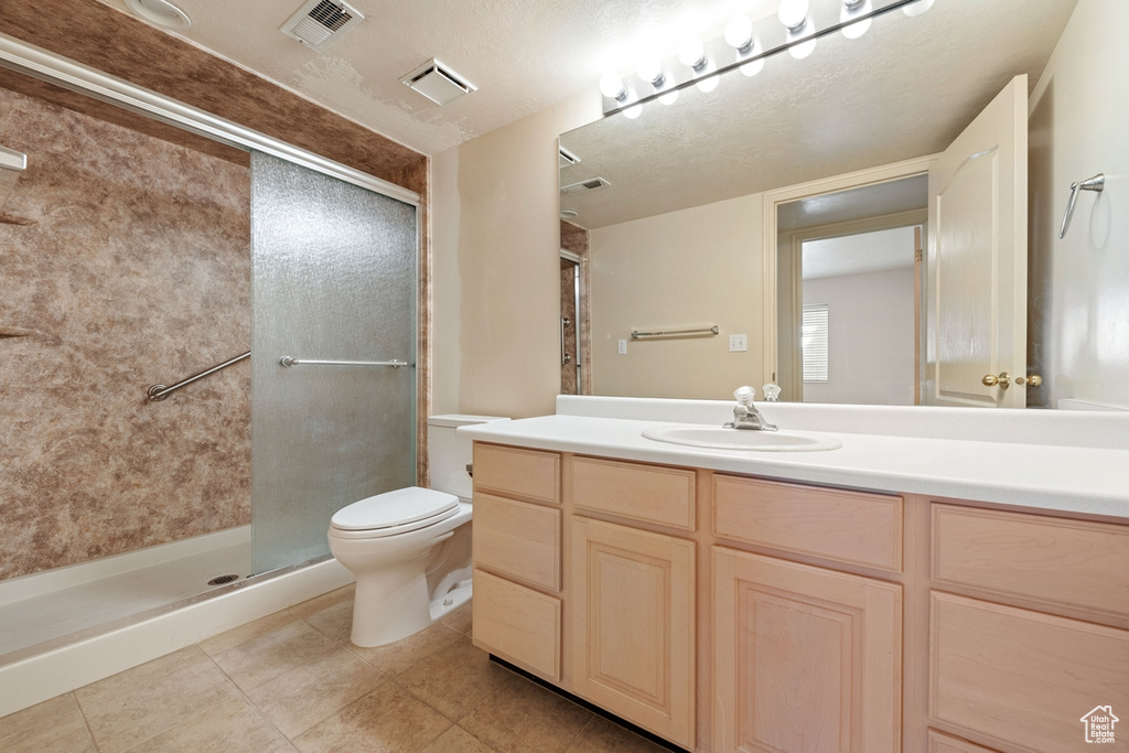 Bathroom featuring toilet, a shower with shower door, tile flooring, a textured ceiling, and vanity