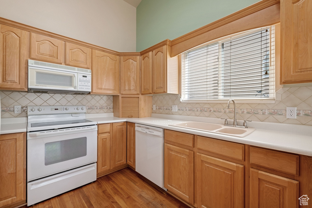 Kitchen featuring backsplash, light hardwood / wood-style floors, white appliances, and sink