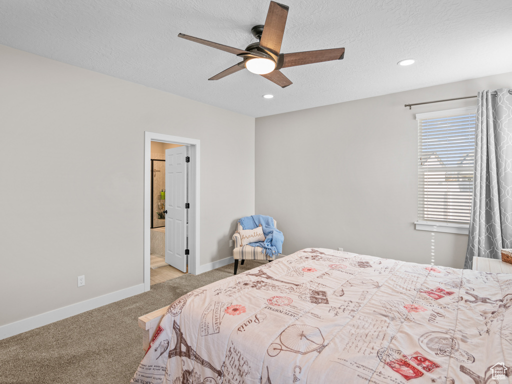 Bedroom featuring light colored carpet, connected bathroom, ceiling fan, and a textured ceiling