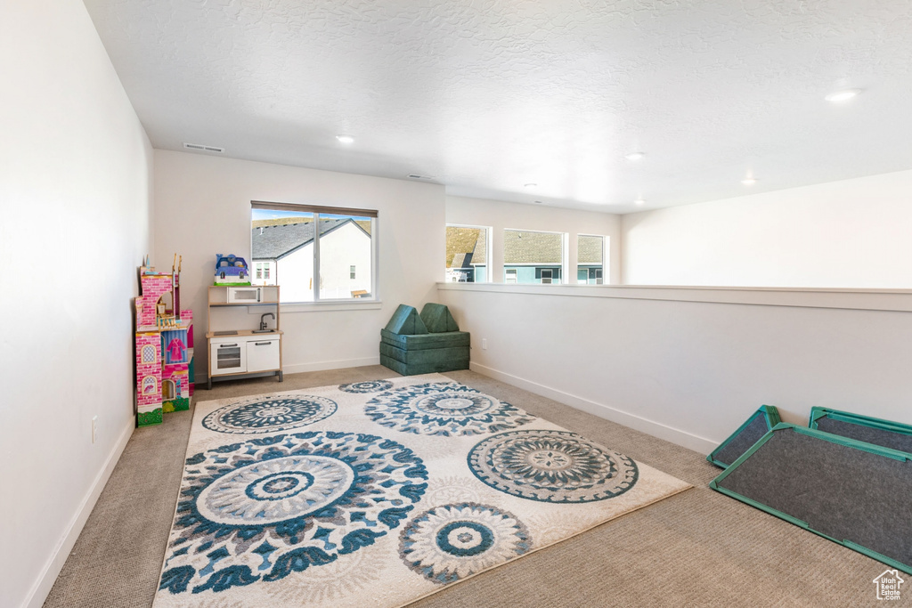 Playroom with a textured ceiling and light colored carpet