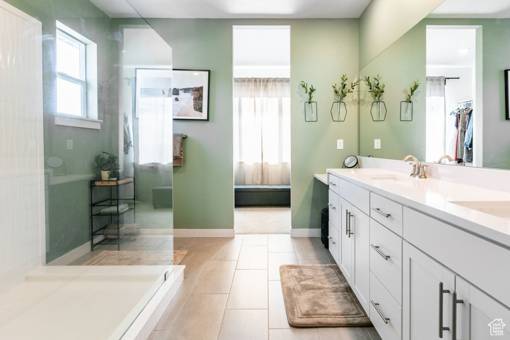 Bathroom with tiled bath, tile floors, and dual bowl vanity