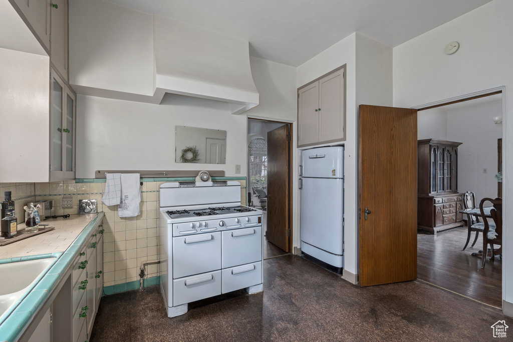 Kitchen featuring tile walls, white appliances, backsplash, dark hardwood / wood-style floors, and sink