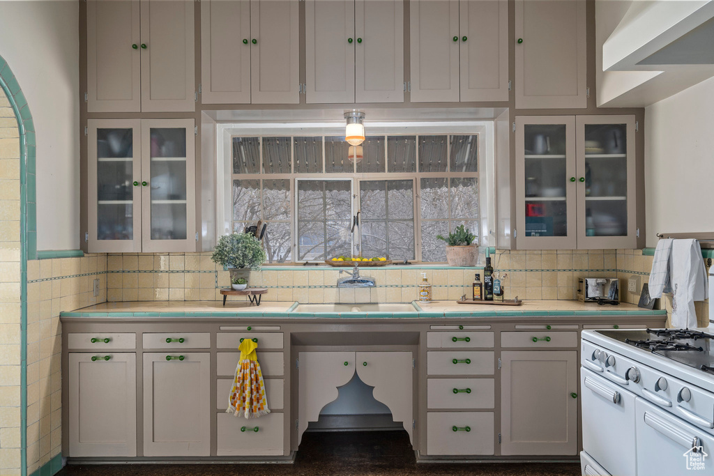 Kitchen with backsplash, white cabinetry, and white range