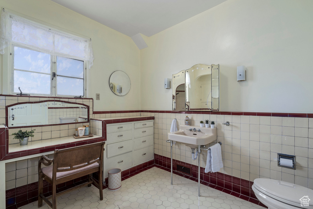 Bathroom with tile walls, tile floors, sink, toilet, and tasteful backsplash