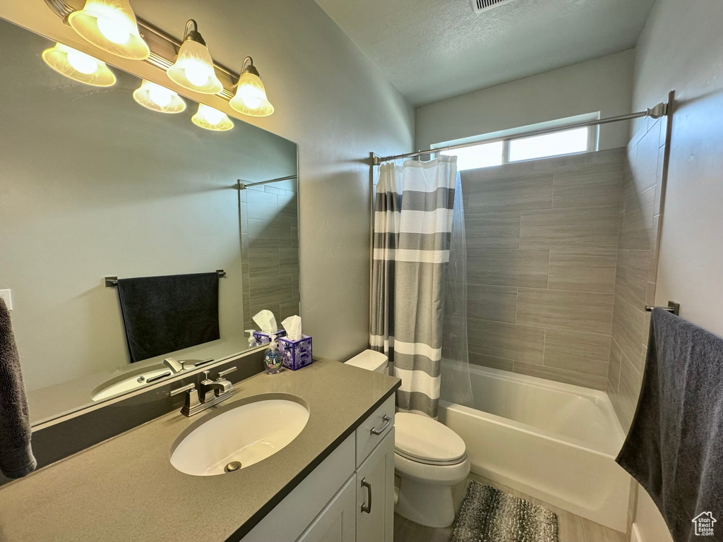Full bathroom featuring shower / bath combo, oversized vanity, and toilet