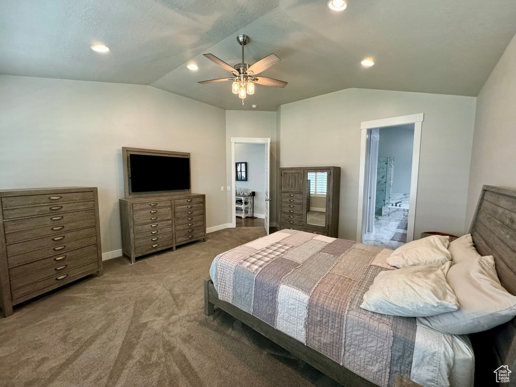 Bedroom with lofted ceiling, ensuite bathroom, dark carpet, and ceiling fan